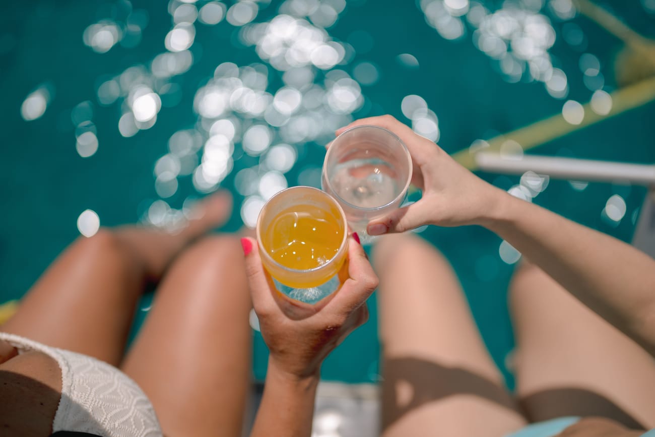 Two drinks held up over the sparkling water
