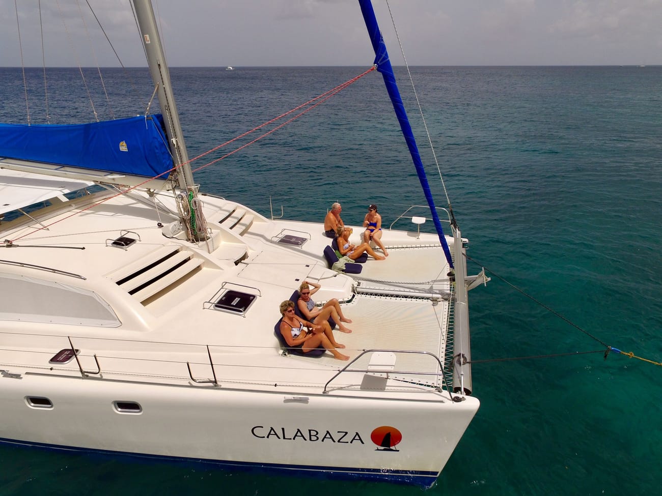 Calabaza at anchor on turquoise water, guests relaxing on the trampoline