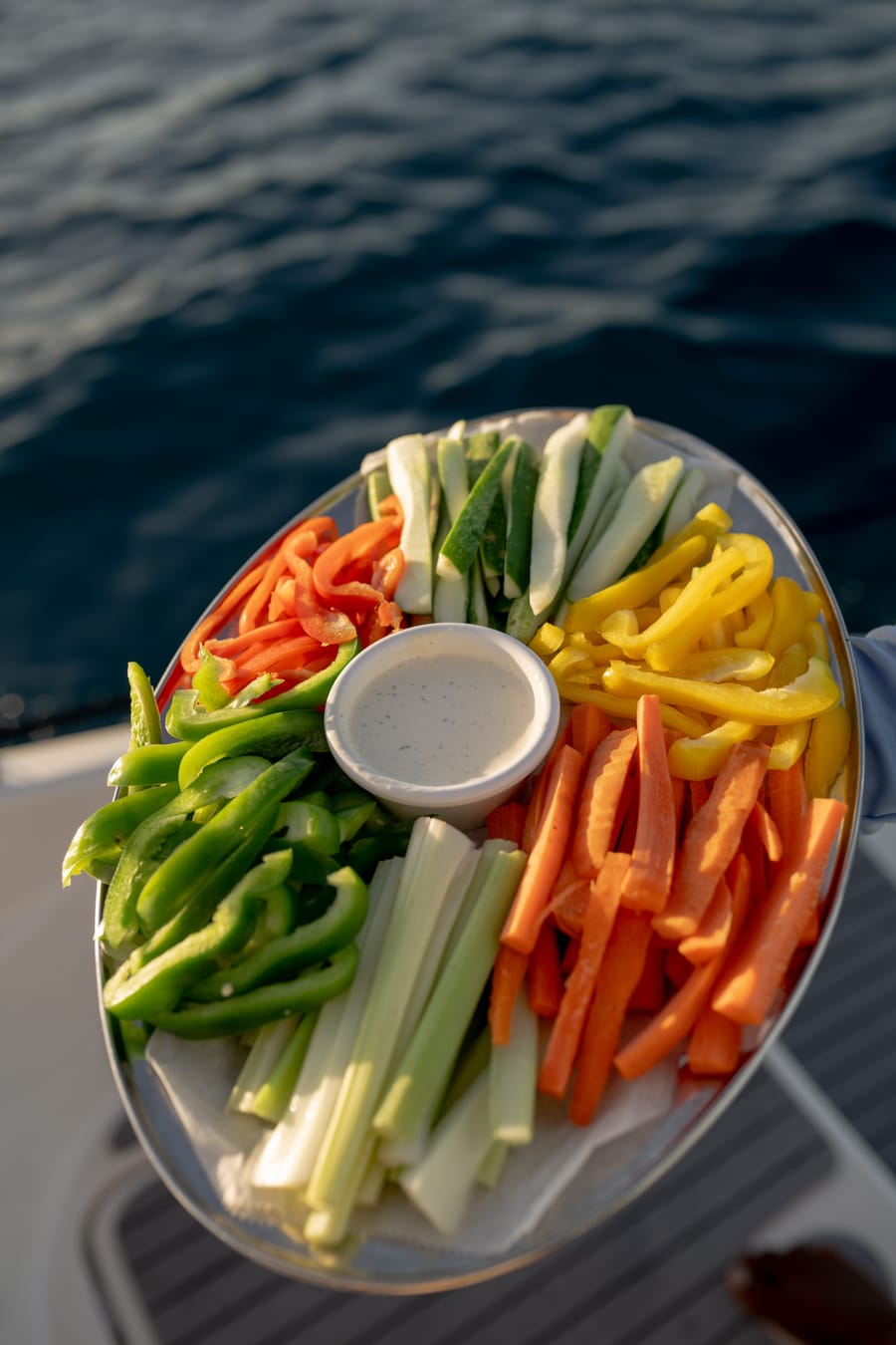 A crew member holding a platter of fresh vegetables and dip