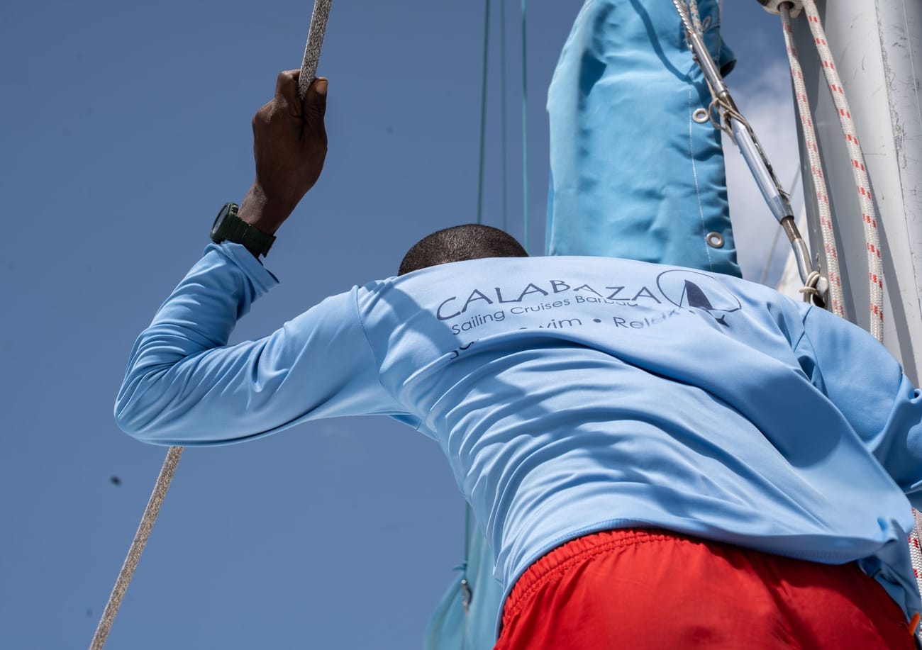 A crew member working the rigging under the sail